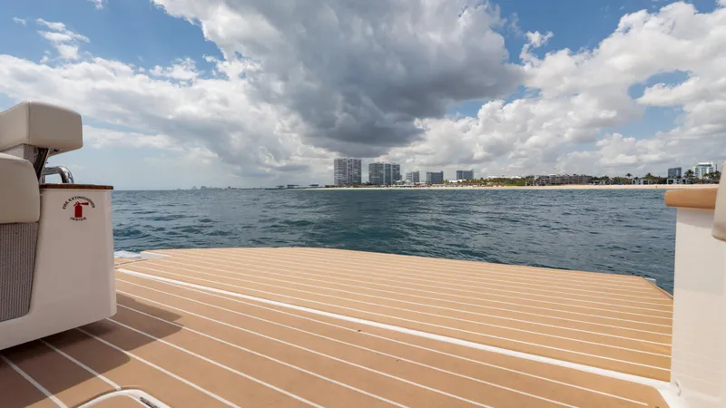Slide: The Image of 2024 Tiara Yachts 48 LE deck overlooking ocean and city skyline under cloudy sky. - 31