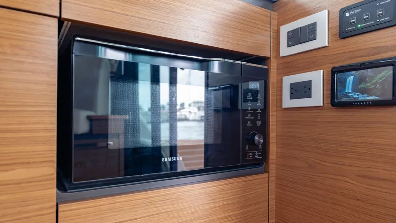 Slide: The Image of Microwave in 2024 Tiara Yachts 48 LE, surrounded by wooden cabinetry and control panels. - 49