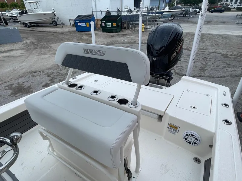 Slide: The Image of 2024 Pathfinder 2200 TRS boat interior with seating and motor, docked outdoors. - 6