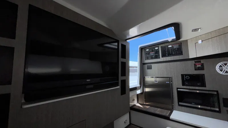 Slide: The Image of Interior of 2023 Monterey 385SS boat featuring a TV, control panel, and appliances. - 37