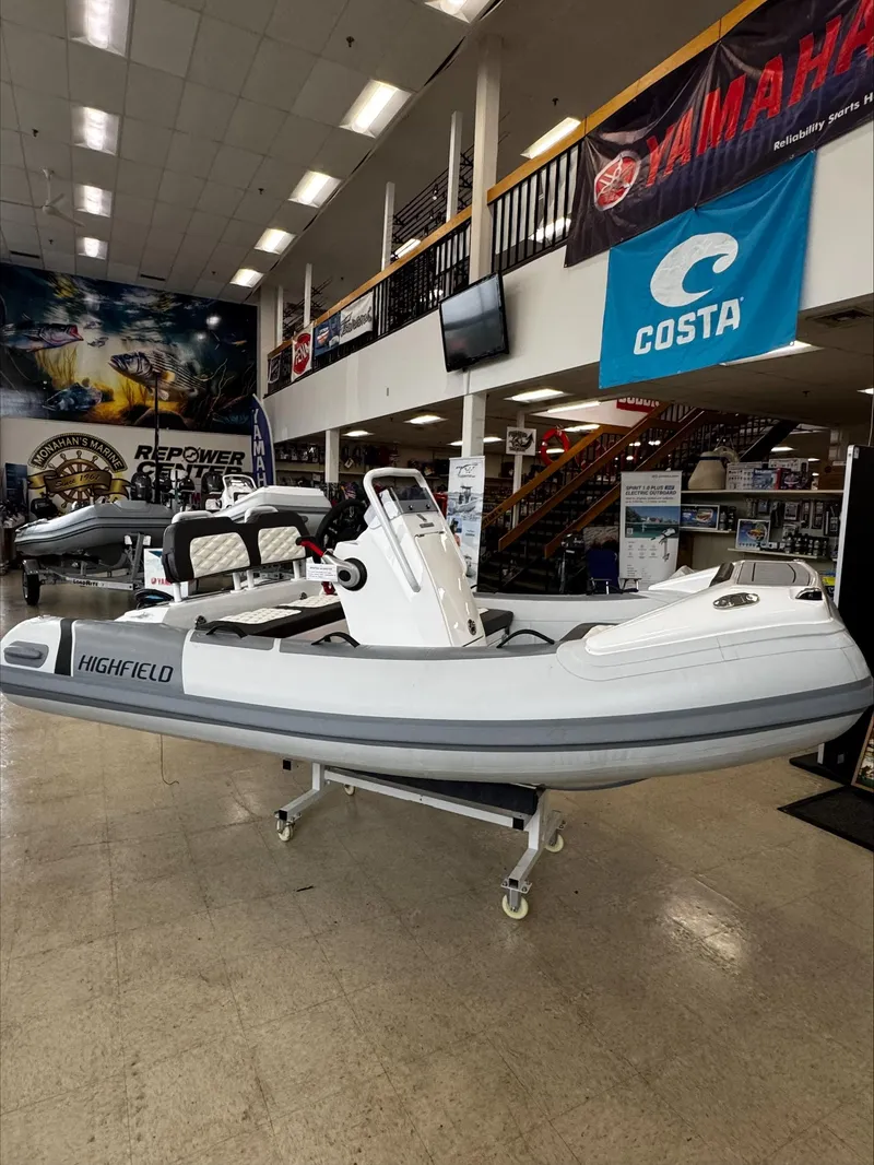 The Image of 2025 Highfield Sport 330 inflatable boat displayed in a showroom with banners. - 0