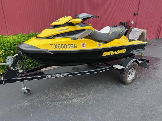 The Image of 2011 Sea-Doo RXT 260 jet ski in yellow on a trailer, parked outdoors. - 0