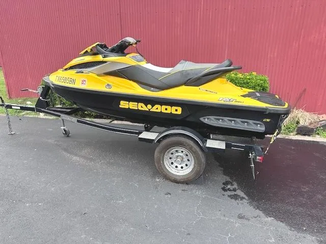 Slide: The Image of 2011 Sea-Doo RXT 260 jet ski on trailer, yellow and black, parked on asphalt. - 2