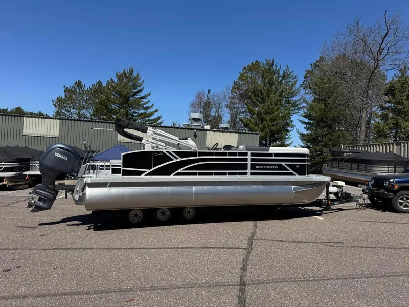 Slide: The Image of 2025 Bennington 22SSB-SPS pontoon boat with Yamaha motor, parked outdoors. - 1