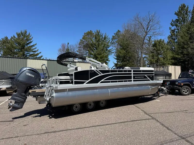 Slide: The Image of 2025 Bennington 22SSB-SPS pontoon boat with Yamaha engine, parked outdoors. - 2