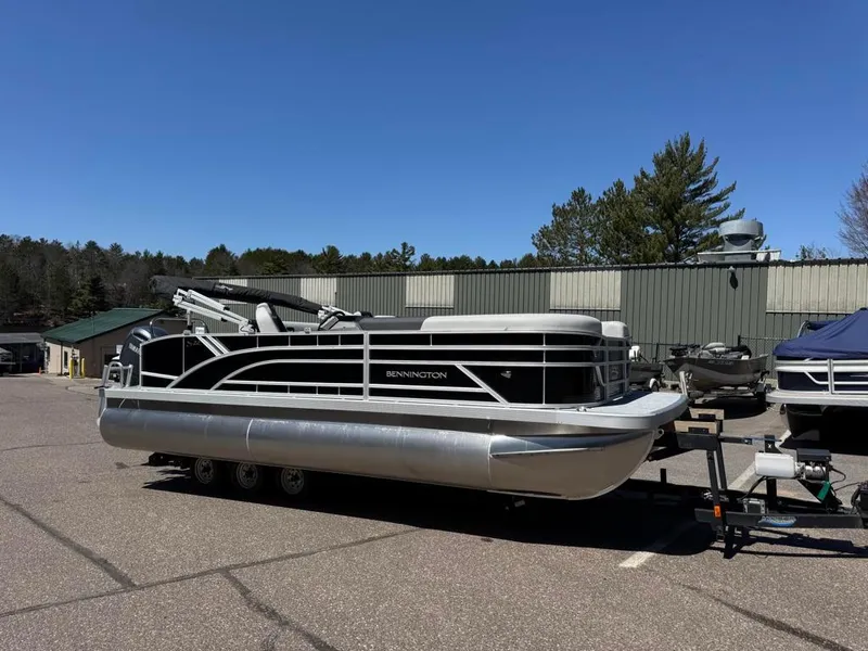 Slide: The Image of 2025 Bennington 22SSB-SPS pontoon boat on trailer in parking lot, clear sky background. - 3