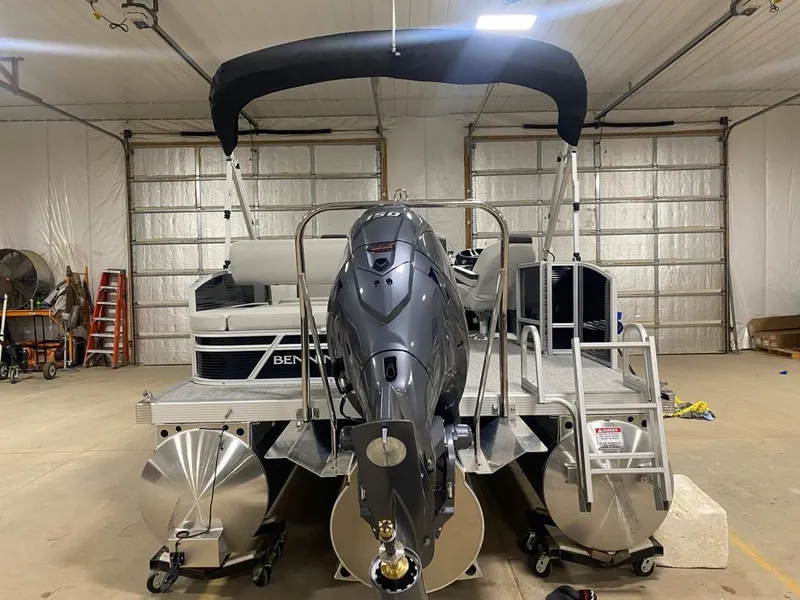 Slide: The Image of 2025 Bennington 22SSB-SPS pontoon boat in a garage, rear view with motor and ladder. - 9