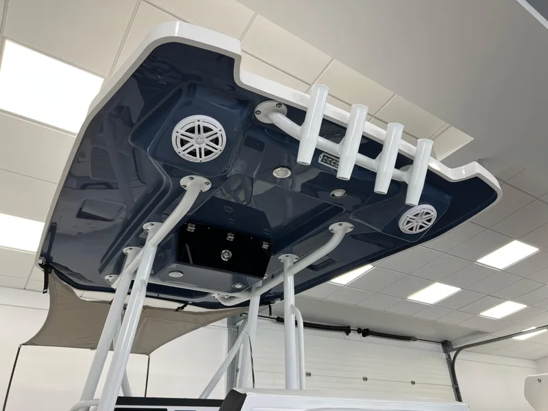 Slide: The Image of 2025 Blackfin 222CC boat T-top with speakers and rod holders in a showroom. - 11