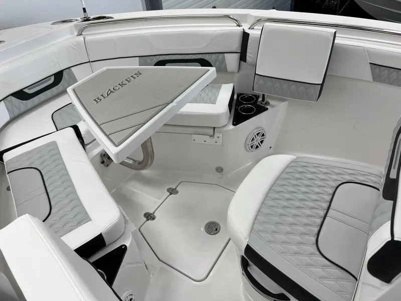 Slide: The Image of 2025 Blackfin 222CC boat interior with white seating, table, and speaker system. - 16