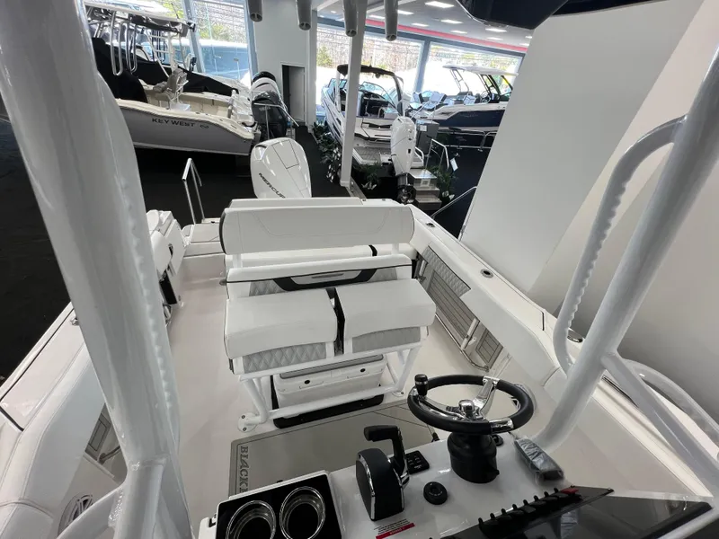 Slide: The Image of 2025 Blackfin 222CC boat interior with steering wheel and seating in showroom. - 20