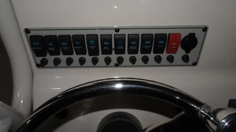 Slide: The Image of Control panel of a 2015 Key West 219 FS boat with various switches and steering wheel. - 15