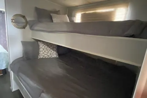 Slide: The Image of Bunk beds in a 1985 Sumerset 60 X 14 houseboat, featuring cozy gray bedding. - 10