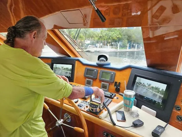 Slide: The Image of Person steering 2003 Hargrave Sky Lounge yacht, surrounded by navigation equipment and scenic waterway view. - 10
