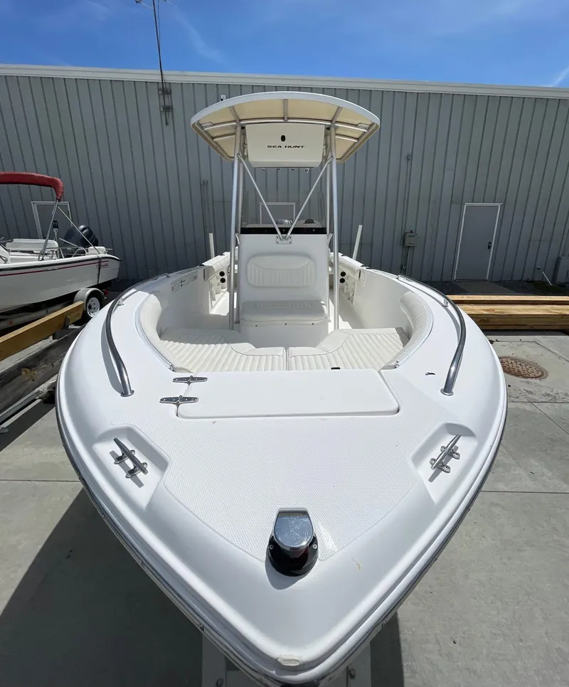 Slide: The Image of 2007 Sea Hunt Triton 207 boat with T-top, docked outdoors under clear sky. - 14