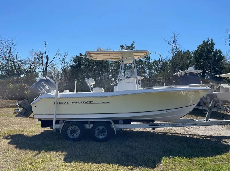 Slide: The Image of 2007 Sea Hunt Triton 207 boat on trailer, parked outdoors under clear blue sky. - 4