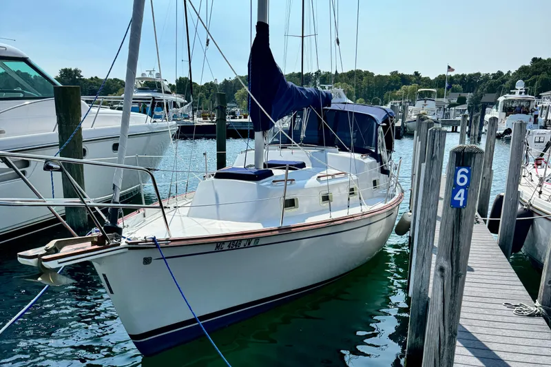 Slide: The Image of 1978 Bombay Clipper Sloop docked at a marina, surrounded by calm water and other boats. - 0