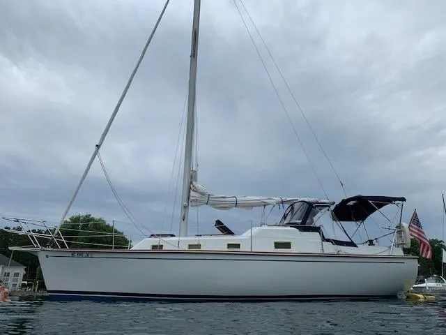 Slide: The Image of 1978 Bombay Clipper Sloop sailboat on calm water under cloudy sky. - 12