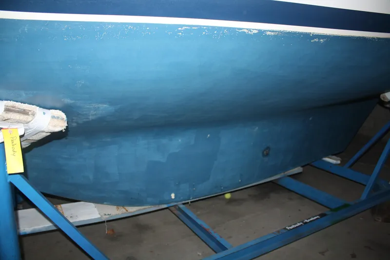 Slide: The Image of 1978 Bombay Clipper Sloop hull on blue stand, showcasing boat's underside. - 18