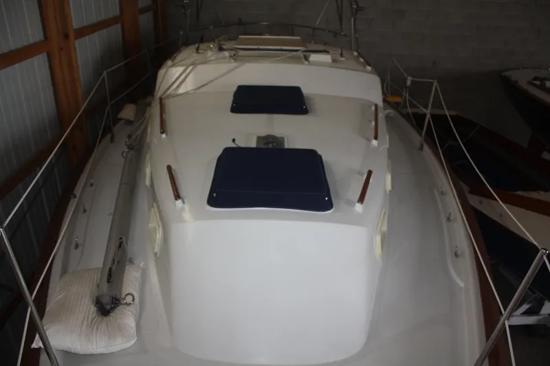Slide: The Image of 1978 Bombay Clipper Sloop sailboat in storage, featuring a clean white deck and blue hatches. - 25