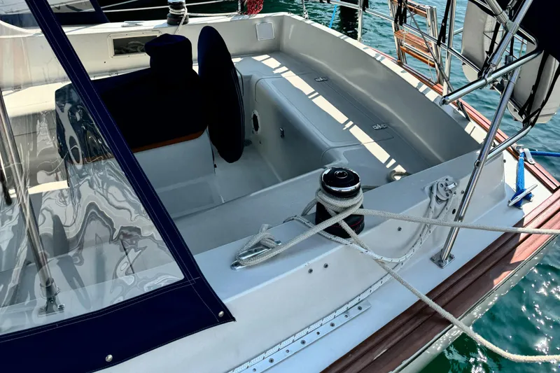 Slide: The Image of 1978 Bombay Clipper Sloop cockpit with ropes and seating, docked on clear water. - 5