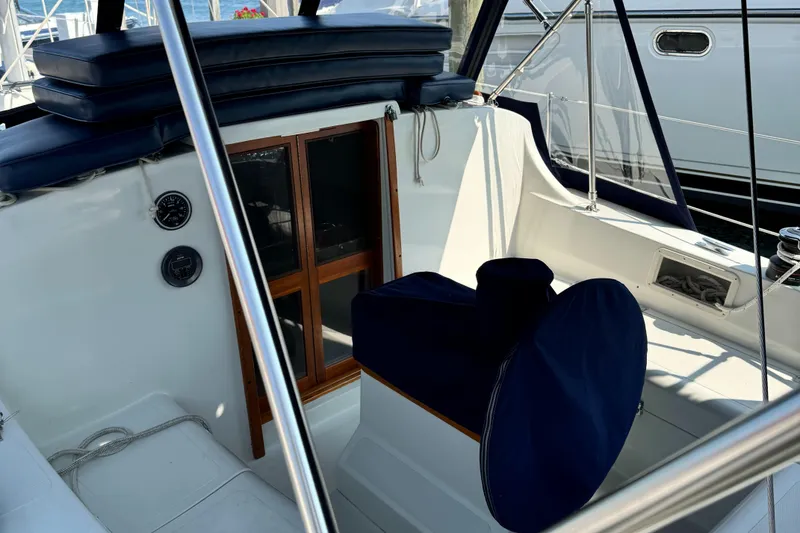 Slide: The Image of 1978 Bombay Clipper Sloop cockpit with navy cushions and wooden cabin doors. - 6