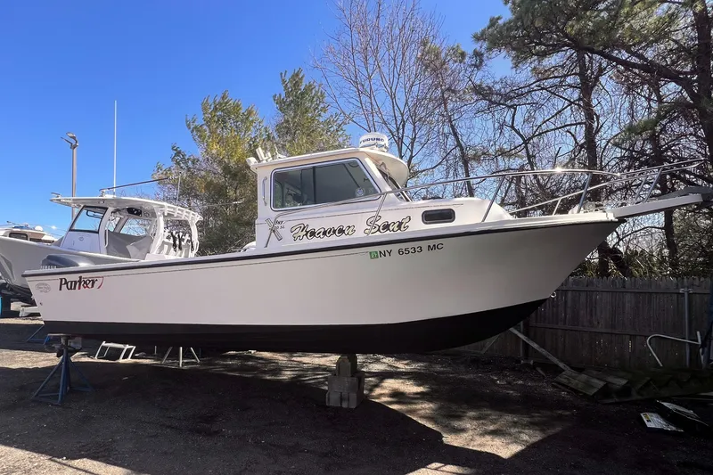 Slide: The Image of 2006 Parker 2320 SL Sport Cabin boat on dry dock, surrounded by trees. - 0