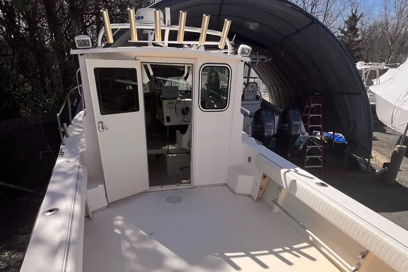 Slide: The Image of 2006 Parker 2320 SL Sport Cabin boat with open deck and cabin, stored outdoors. - 4