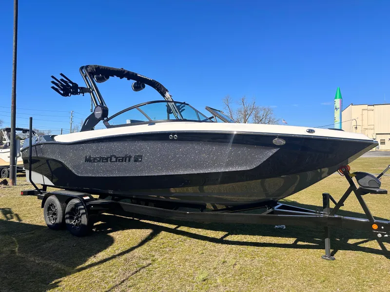 Slide: The Image of 2025 MasterCraft X24 boat on trailer, displayed outdoors under clear blue sky. - 0