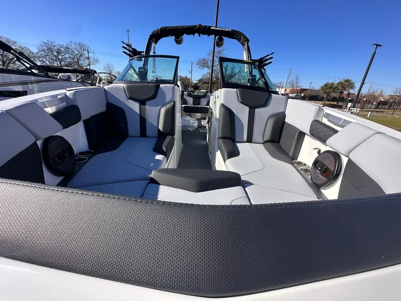 Slide: The Image of 2025 MasterCraft X24 boat interior with modern seating and speakers, under clear blue sky. - 1