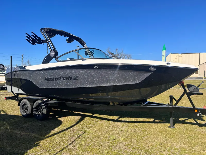Slide: The Image of 2025 MasterCraft X24 boat on trailer, sleek design, sunny day, outdoor display. - 2