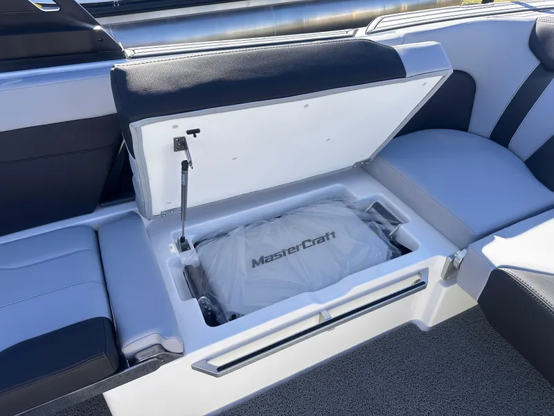 Slide: The Image of 2025 MasterCraft X24 boat storage compartment with open lid, showcasing interior design. - 7