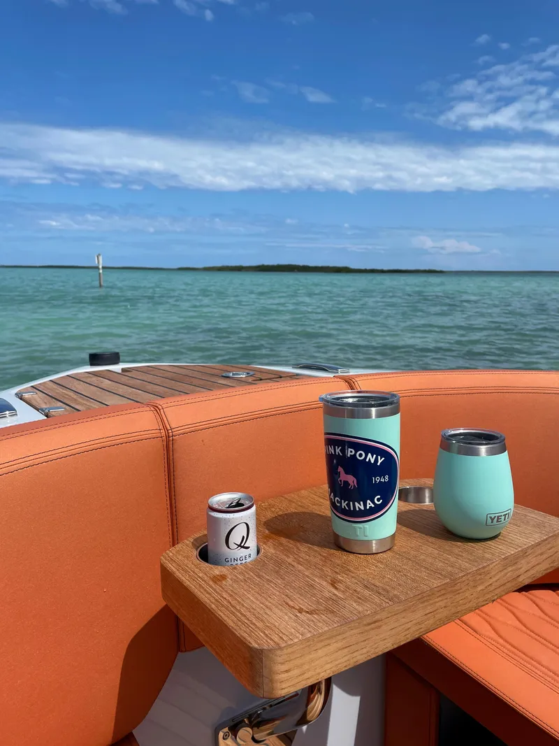 Slide: The Image of Cranchi 26 Rider 2022 boat with drinks on deck, overlooking serene blue waters. - 16