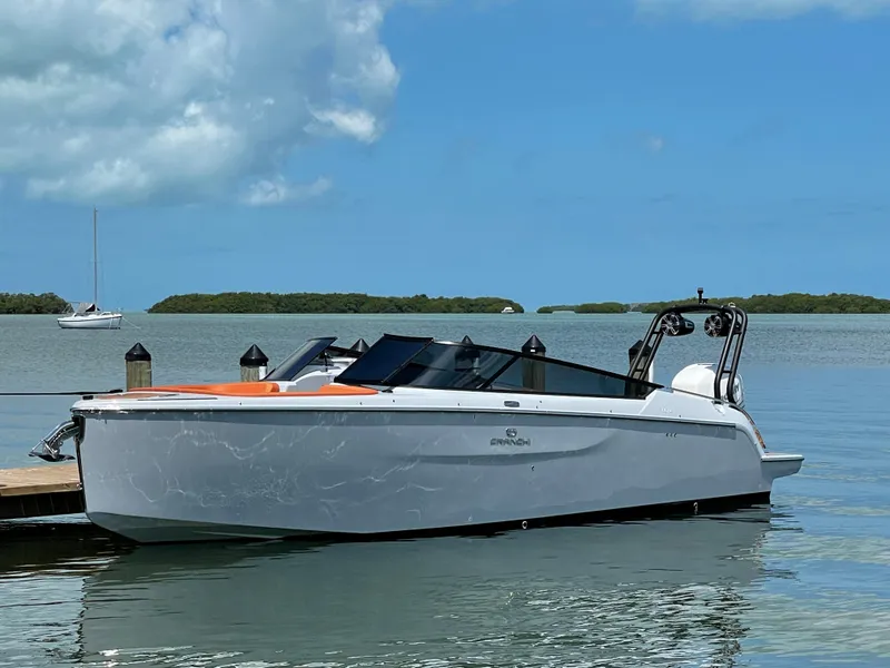 Slide: The Image of 2022 Cranchi 26 Rider boat docked on calm water under a clear blue sky. - 2