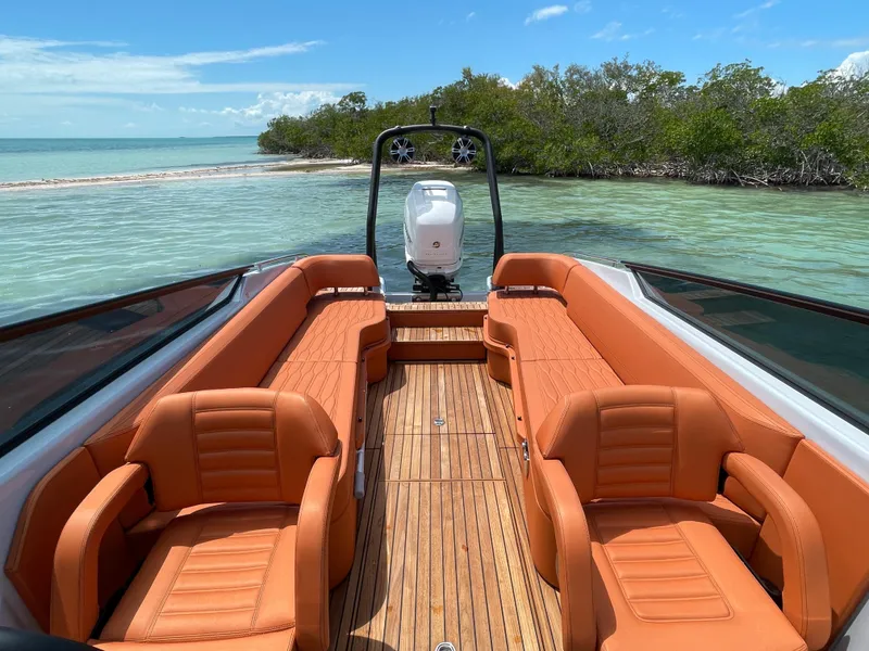 Slide: The Image of 2022 Cranchi 26 Rider boat with orange seating, docked near a scenic shoreline. - 25