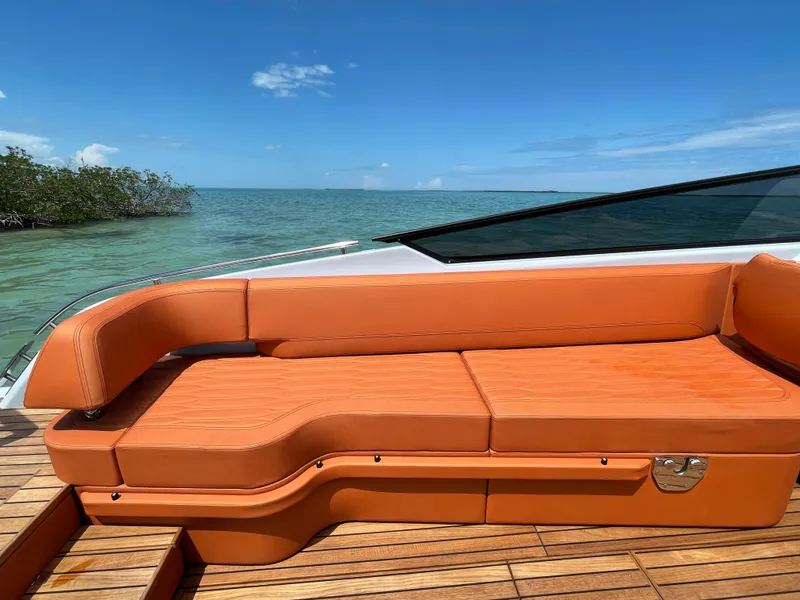 Slide: The Image of 2022 Cranchi 26 Rider boat with orange seating, wooden deck, and ocean view. - 29