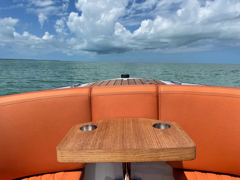 Slide: The Image of 2022 Cranchi 26 Rider boat with orange seating and wooden table on open water. - 32