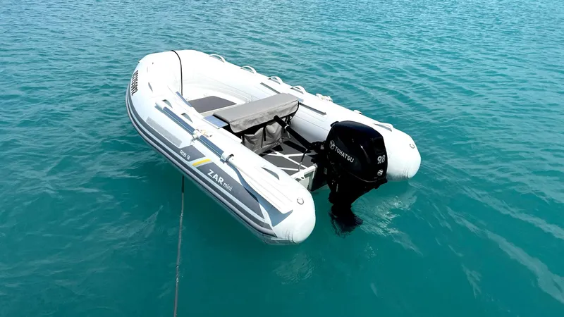 Slide: The Image of A white inflatable boat with an outboard motor floating on clear blue water. - 11