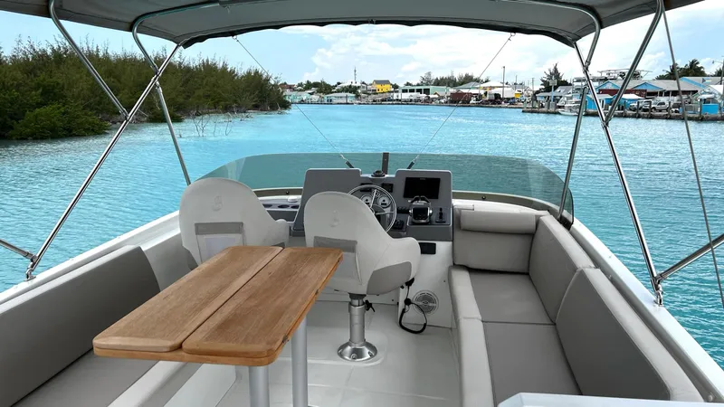 Slide: The Image of 2020 Beneteau Swift Trawler 44 interior with helm, seating, and table on calm water. - 12