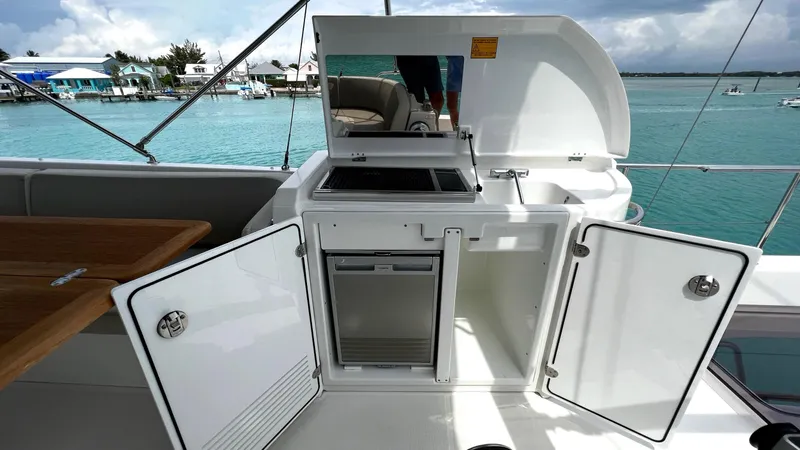 Slide: The Image of Outdoor kitchenette on 2020 Beneteau Swift Trawler 44, featuring storage and grill, near turquoise waters. - 14