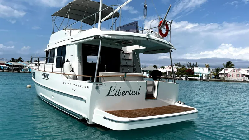 Slide: The Image of 2020 Beneteau Swift Trawler 44 on water, rear view, clear sky, docked nearby. - 7