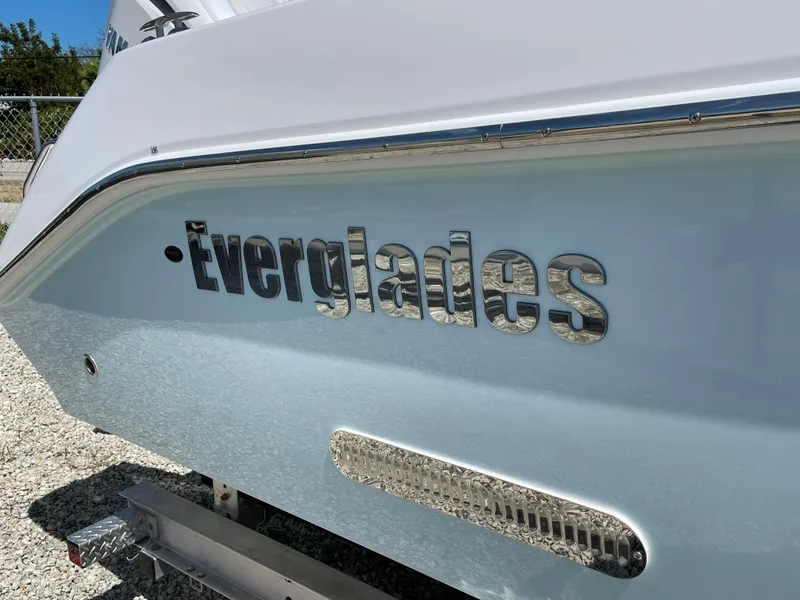 Slide: The Image of 2024 Everglades 285CC boat, close-up of logo on hull, parked on gravel. - 3