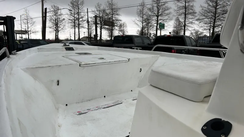 Slide: The Image of 2000 Blazer 1860 boat deck with storage compartments, parked near trees and vehicles. - 12