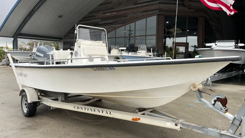 Slide: The Image of 2000 Blazer 1860 boat on trailer, parked outside a building with an American flag. - 2