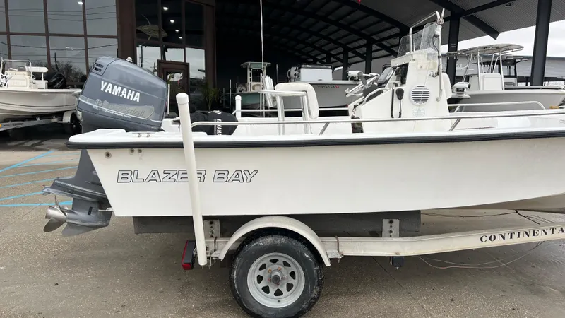 Slide: The Image of 2000 Blazer 1860 boat with Yamaha motor on trailer, parked outside a showroom. - 3