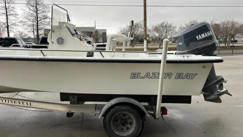 Slide: The Image of 2000 Blazer 1860 boat on trailer with Yamaha outboard motor, parked outdoors. - 7