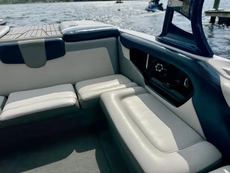 Slide: The Image of Interior of a 2011 Nautique 200V boat with white and blue seating by the water. - 6
