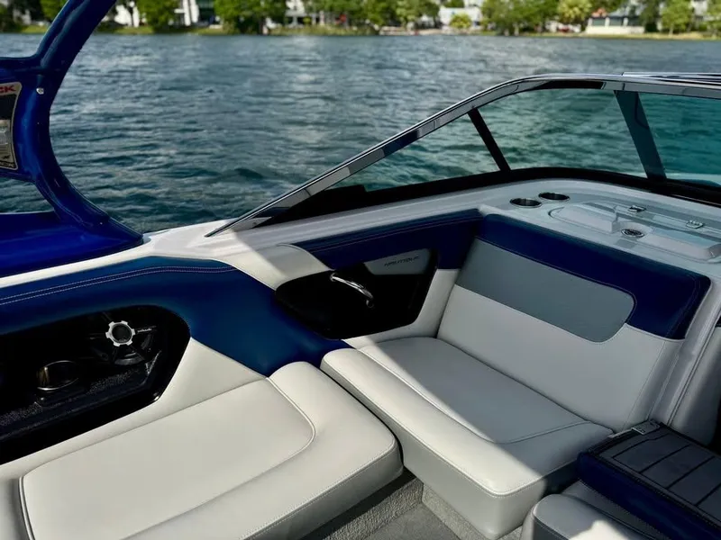 Slide: The Image of 2011 Nautique 200V boat interior with blue and white seating, near a lake. - 8