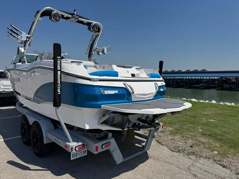 Slide: The Image of 2019 MasterCraft X24 boat on trailer near waterfront, featuring sleek design and vibrant blue accents. - 10