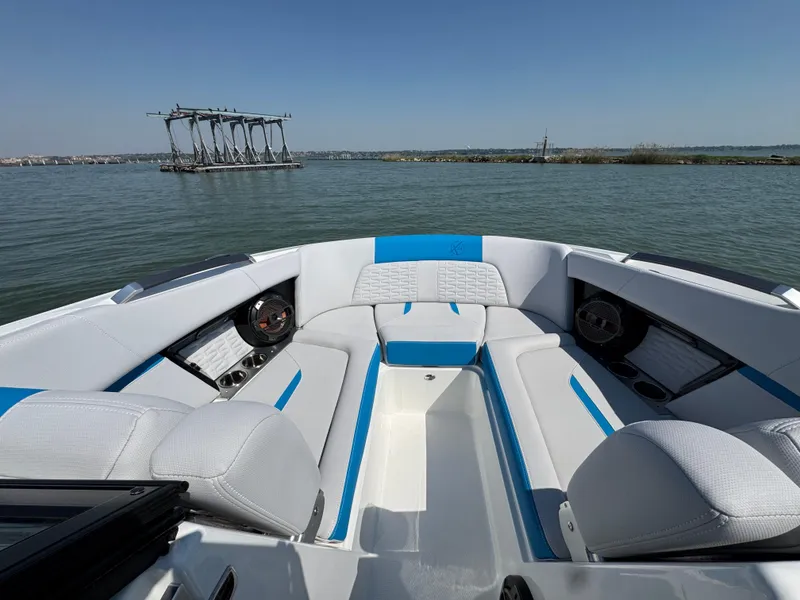 Slide: The Image of 2019 MasterCraft X24 boat interior with blue and white seating on a calm lake. - 12