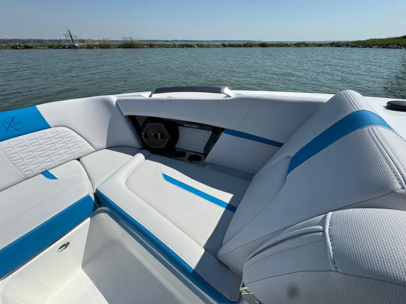 Slide: The Image of 2019 MasterCraft X24 boat interior with blue and white seating on a sunny day. - 13